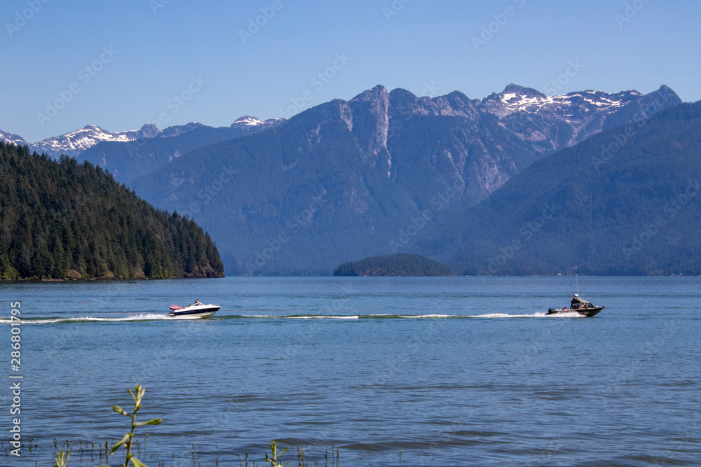 A boat driving on the water with mountains in the background.
