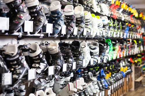 Different models of boots for alpine skiing on shelves in shop