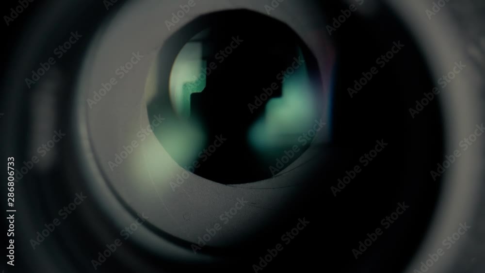 Adjusting aperture camera lens. The camera iris slowly opens and then closes. Aperture blades opening and closing slowly. Camera lens aperture close up.