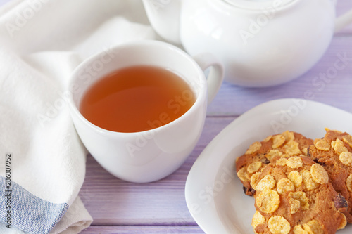 Cup of tea with cookies over lilac wooden background