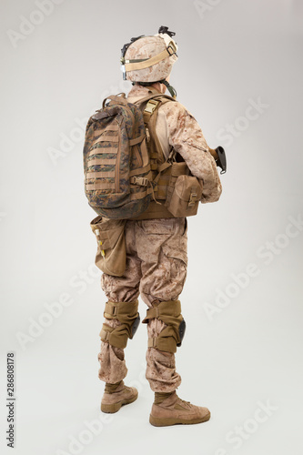 Soldier in US marines uniform with rifle on light grey background, studio shot