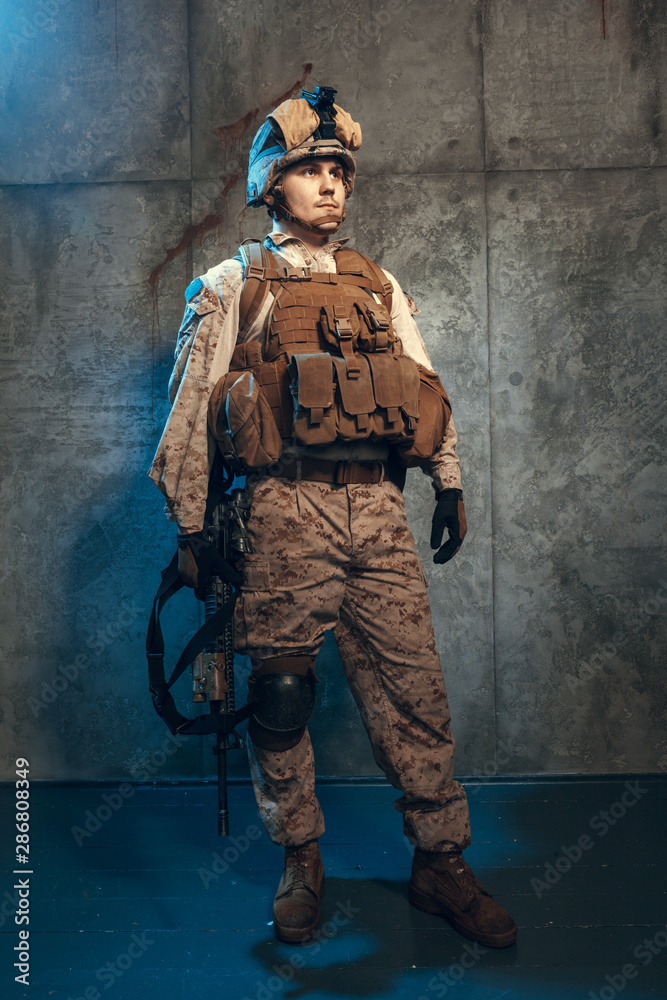 Young man in military outfit a mercenary soldier in modern times on a dark background in studio Young man in military outfit a mercenary soldier in modern times on a dark background in studio