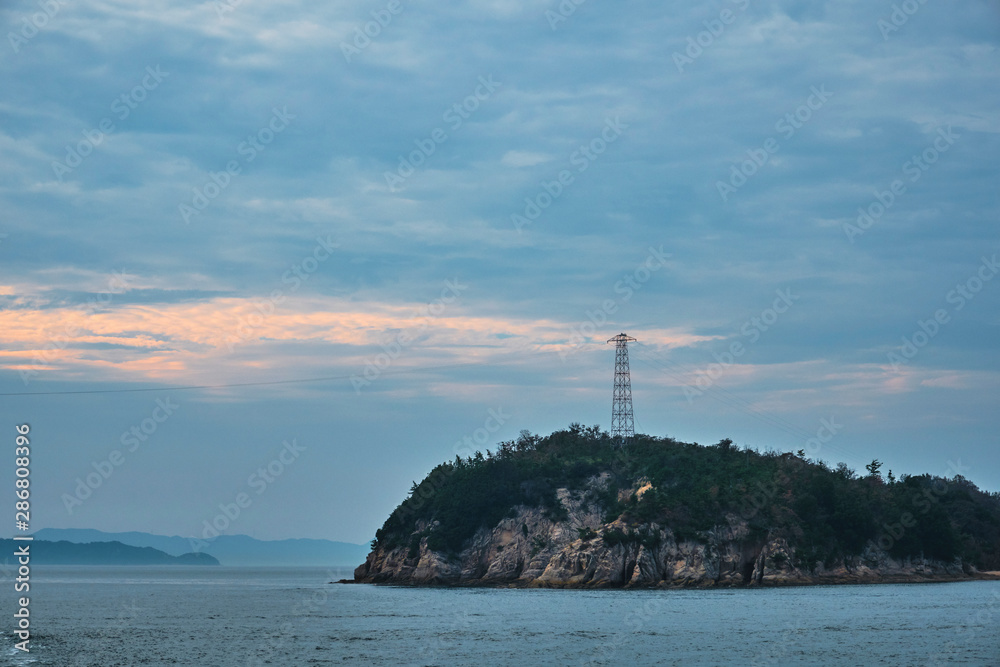 夕暮れ時の島の鉄塔と電線