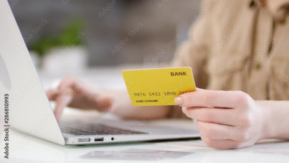 Close up view of hands of unrecognizable woman typing credit card information on laptop while making online payment Close up view of hands of unrecognizable woman typing credit card information on laptop while making online payment