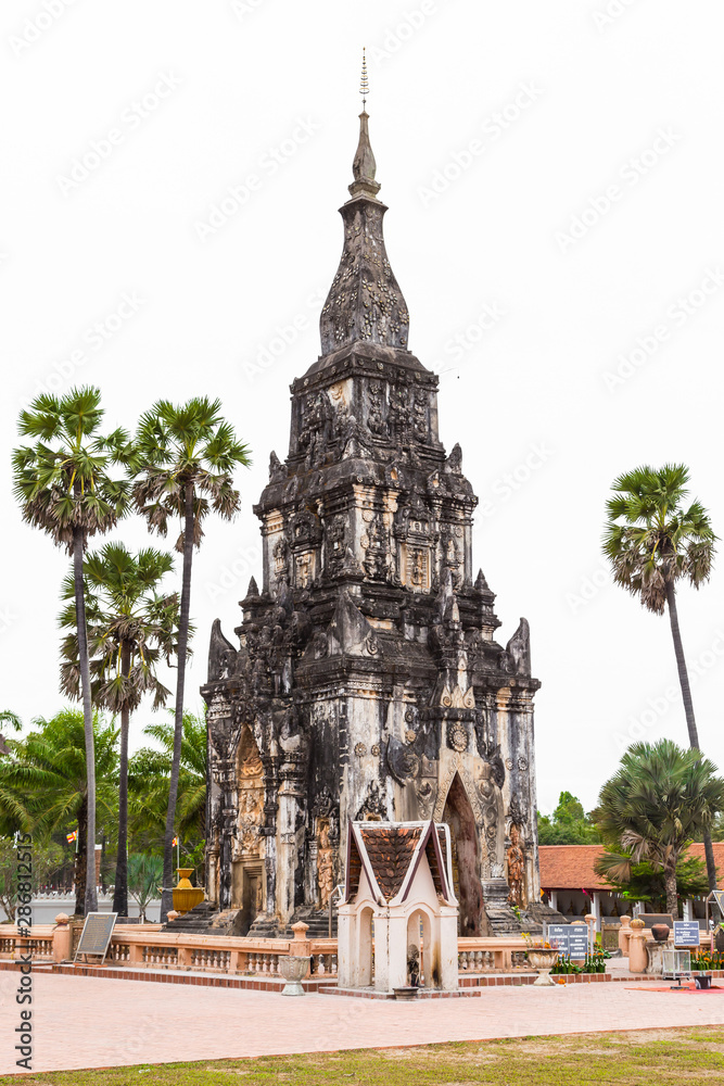 Savannakhet Laos-December 28 2018 :  Travel attraction at That Ing Hang, Ancient herritage of old pagoda with palm trees on white background (Editorial image)