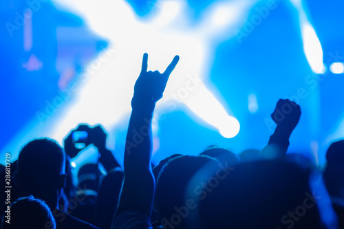 Fans cheering musicians on stage at live rock music concert
