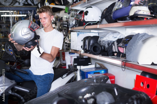 Motorcyclist choosing helmet for motorbike in bike shop
