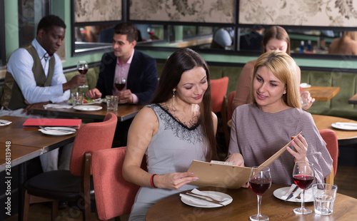 Two female friends with menu card in restaurant