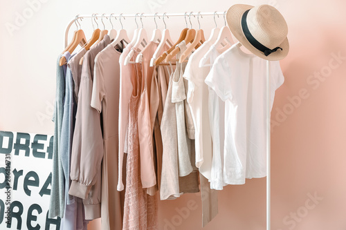 Rack with clothes near color wall in room photo