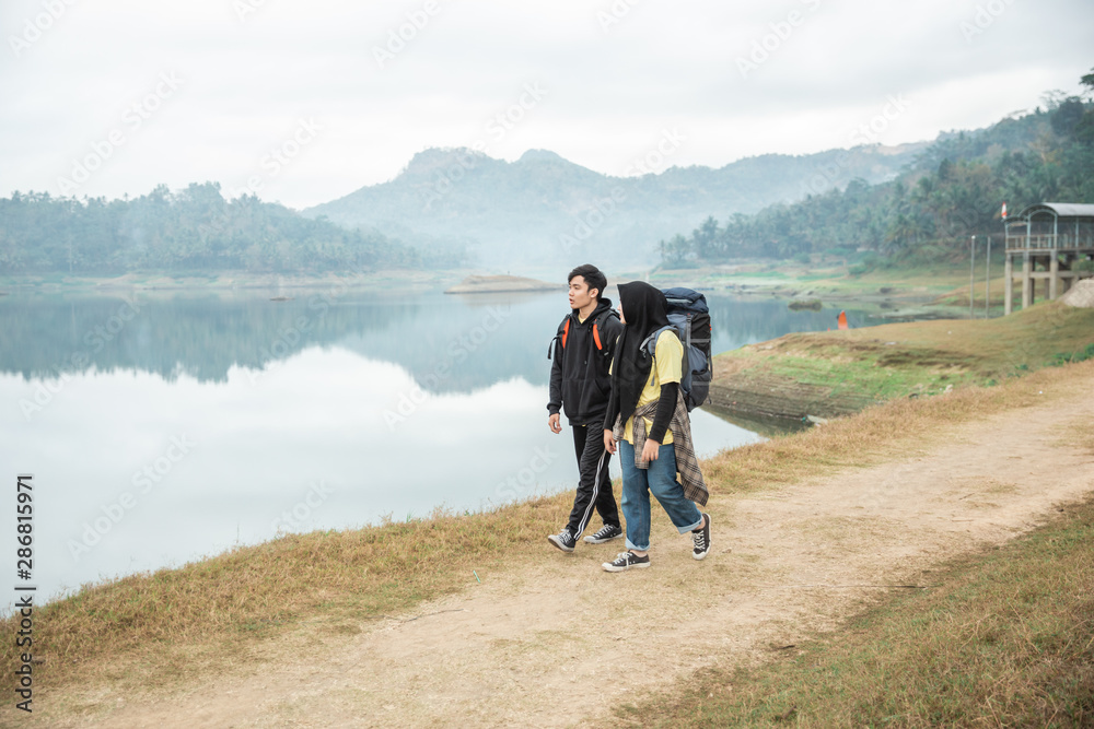 Muslim couple tourist with backpack in the side lake