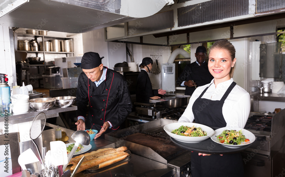 Waitress holding cooked meals in kitchen