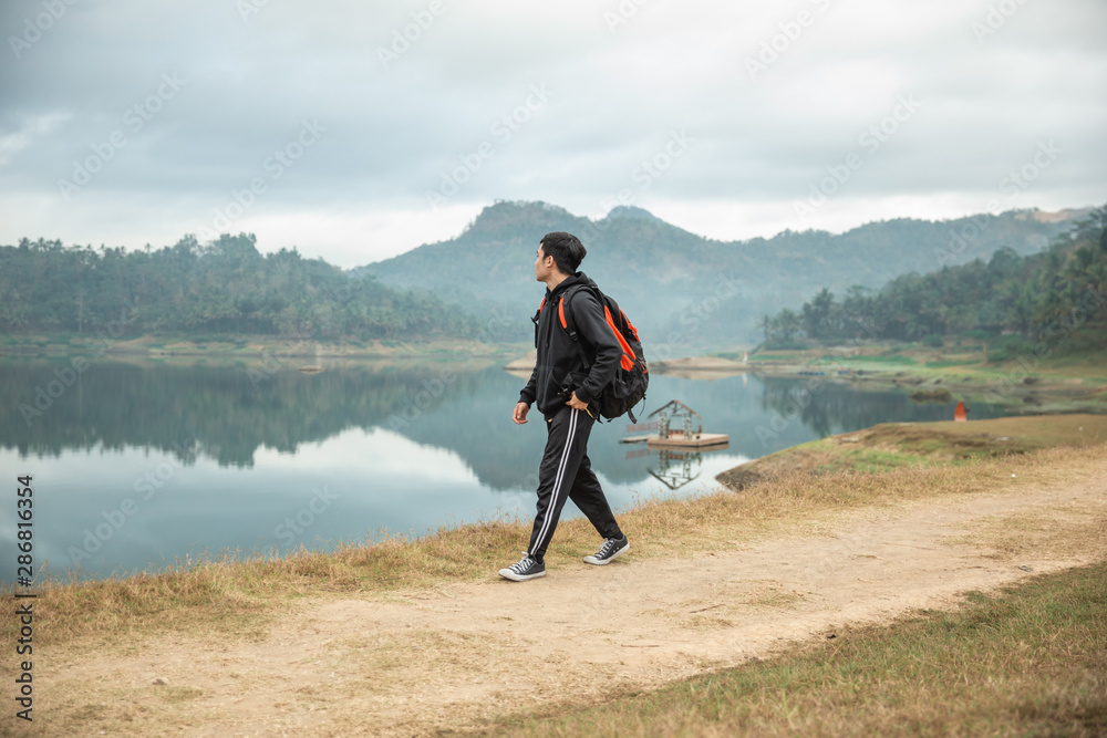 hikers with backpacks enjoying lake view, walking side the lake
