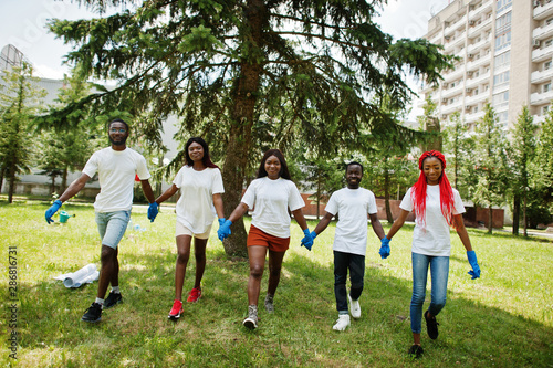 Group of happy african volunteers hold hands together in park. Africa volunteering, charity, people and ecology concept.