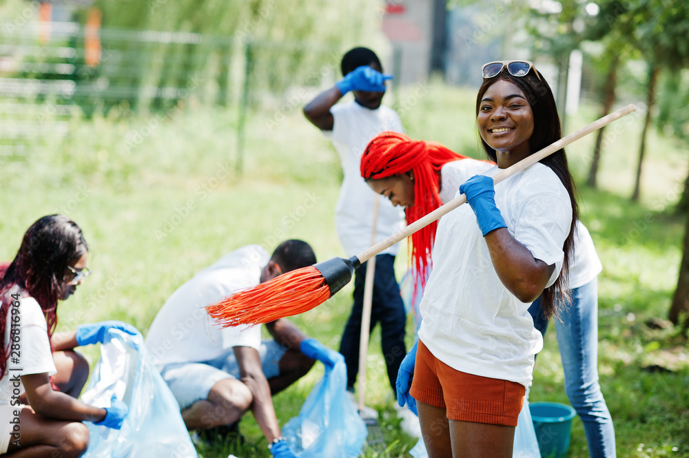 Group of happy african volunteers with garbage bags cleaning area in park. Africa volunteering, charity, people and ecology concept. Group of happy african volunteers with garbage bags cleaning area in park. Africa volunteering, charity, people and ecology concept.