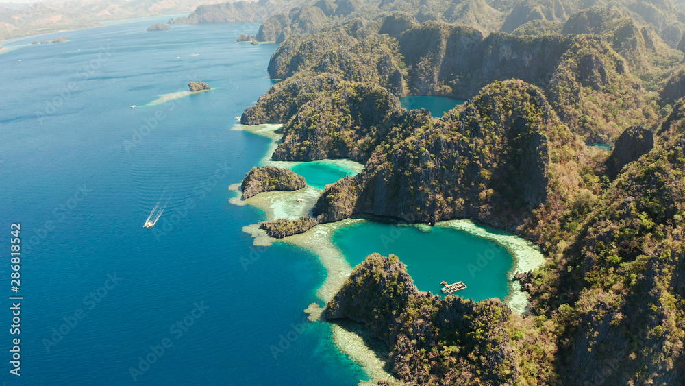 Tourist boats around the beautiful big and small lagoons, aerial view. lagoon, mountains covered with forests.coves with blue water among the rocks. Seascape, tropical landscape. Palawan, Philippines