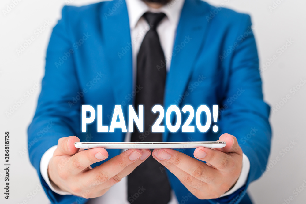 Handwriting text writing Plan 2020. Conceptual photo detailed proposal doing achieving something next year Businessman in blue suite with a tie holds lap top in hands Handwriting text writing Plan 2020. Conceptual photo detailed proposal doing achieving something next year Businessman in blue suite with a tie holds lap top in hands