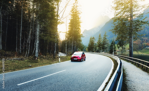 Car on the mountain road curve in the forest, sunset scenery. Alpine road. Location - Ramsau parkland in Germany, near Hintersee Lake, Europe.