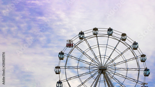 Empty Observation wheel on the background of blue sky with white clouds. Horizontal with copy space for text of design about theme park, amusement. Summer. Day time.