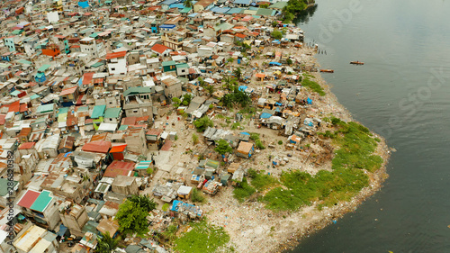 Slums in Manila on the bank of a river polluted with garbage, aerial view. © Alex Traveler