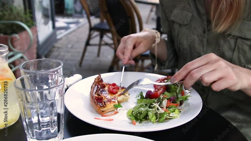 Woman eating tasty greek salad with cake in cafe. Woman eating tasty greek salad with cake in cafe.