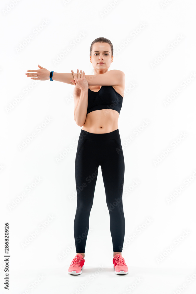 Young sporty blond woman in a black sportswear stretching before exercising isolated over white background. Young sporty blond woman in a black sportswear stretching before exercising isolated over white background.