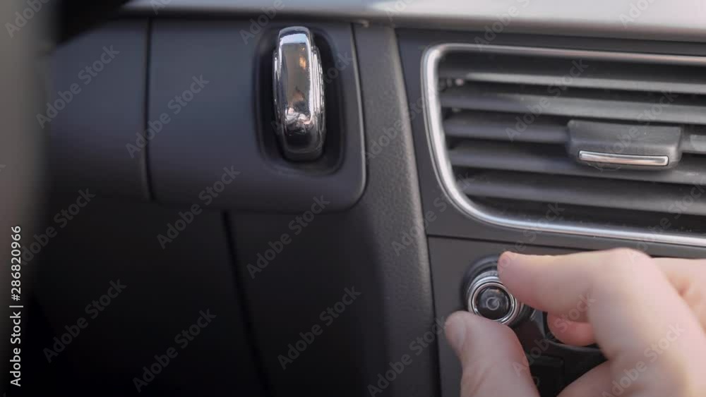 In the frame, a man s hand and a car audio volume knob. The driver or passenger adjusts the volume level of the music. In the frame, a man s hand and a car audio volume knob. The driver or passenger adjusts the volume level of the music.