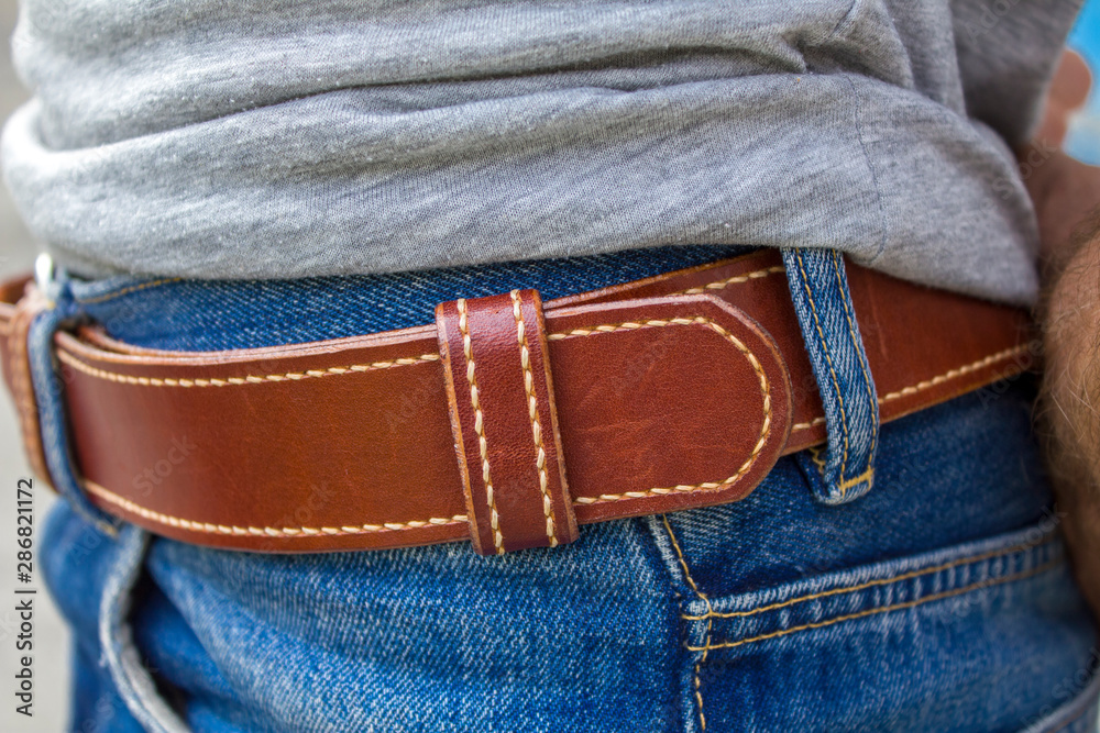 bright red stitched leather belt in blue jeans close-up