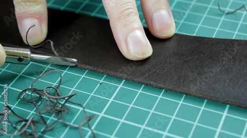 trimming the edge of a leather belt close-up. edge beveller. hands made craft photo