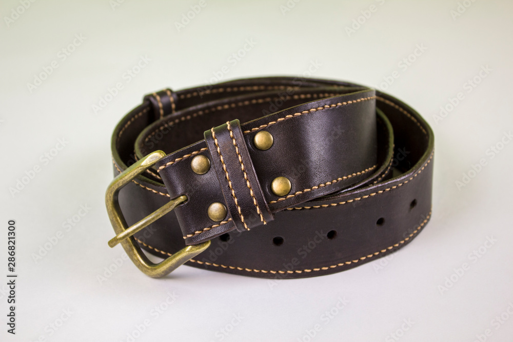 dark brown stitched leather belt with yellow buckle and rivets on a white background dark brown stitched leather belt with yellow buckle and rivets on a white background