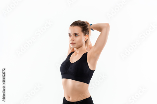 Young sporty blond woman in a black sportswear stretching before exercising isolated over white background. © ianachyrva