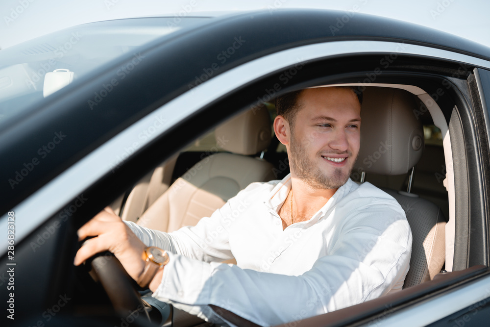 Smiling successful businessman in a white shirt drives his luxary car. Smiling successful businessman in a white shirt drives his luxary car.