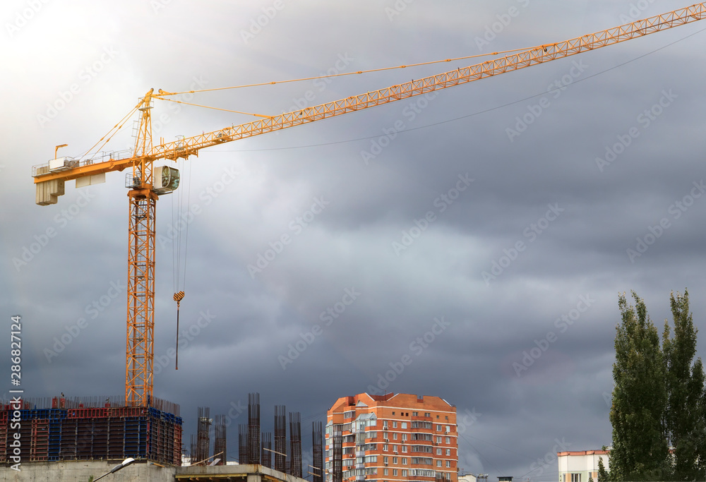 construction crane and the building against sky with grey clouds