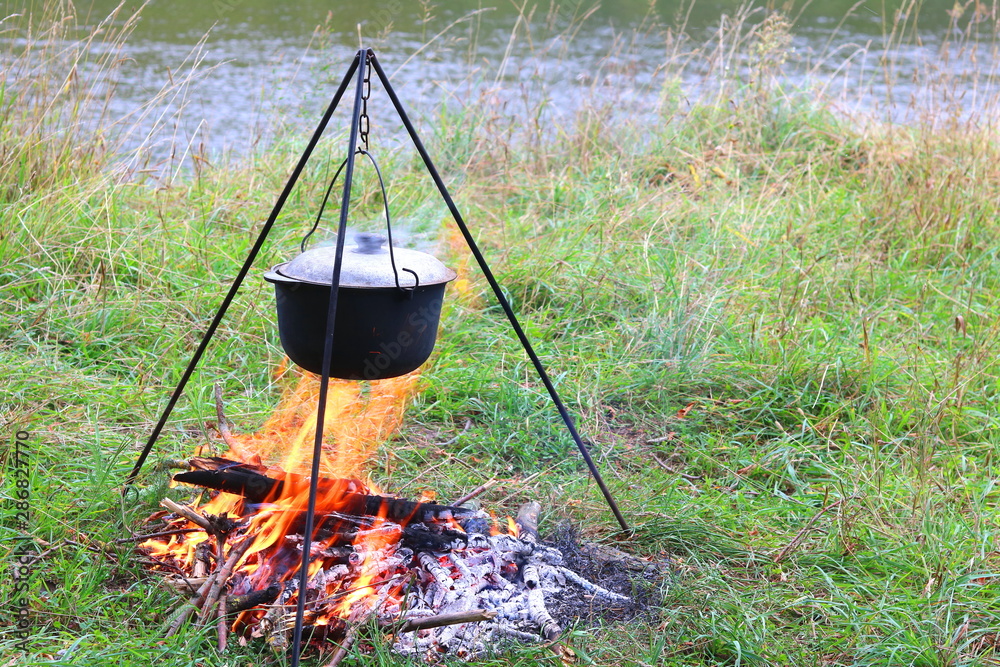 cooking delicious tasty food outdoors on fire in iron pot in summer in good weather with wood from forest cooking delicious tasty food outdoors on fire in iron pot in summer in good weather with wood from forest