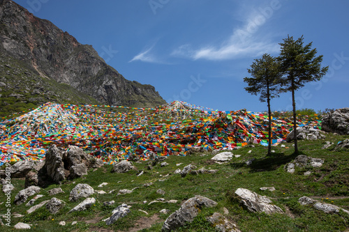 Colorful Tibetan prayer flags on the mountain of Yeliguan, Lintan, Gansu, China with scattered stones and grass. photo