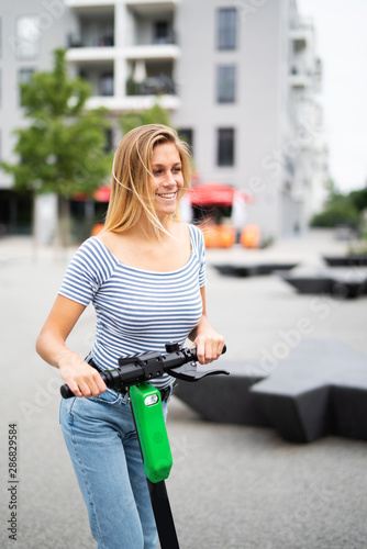 Junge Frau freudig lachend mit einem E-Scooter 