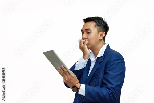 young asian business man looking worried while reading something on his electronic pad
