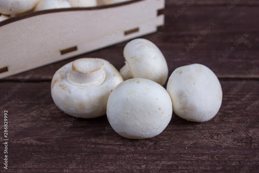 Champignon mushrooms in a wooden tray on a dark background Champignon mushrooms in a wooden tray on a dark background