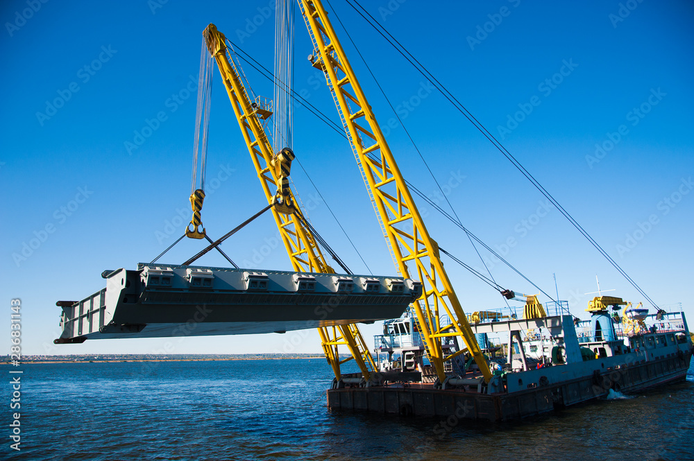 Loading in port. Floating port crane on blue sky background Loading in port. Floating port crane on blue sky background