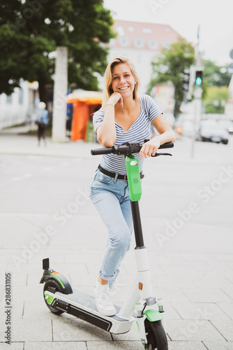 Junge Frau freudig lachend mit einem E-Scooter  photo