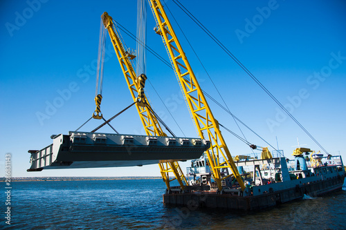 Loading in port. Floating port crane on blue sky background