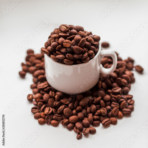 Scattered coffee beans and cup on white windowsill
