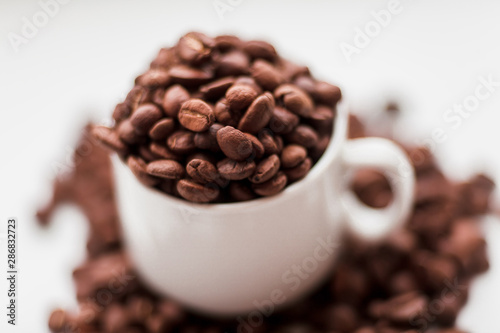 Scattered coffee beans and cup on white windowsill