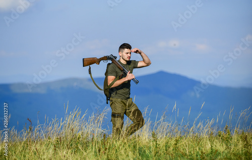 Hunter hold rifle. Nice day for hunt. Hunter spend leisure hunting. Man brutal gamekeeper nature landscape background. Walking in mountains. Hunting masculine hobby concept. Regulation of hunting