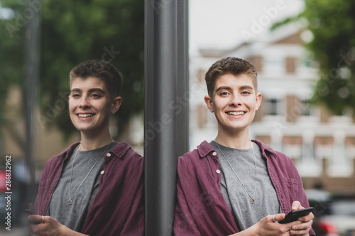 Portrait of gender neutral young adult with smartphone photo