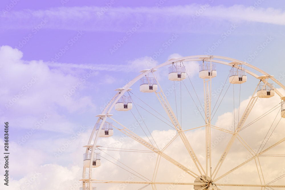 Fototapeta premium Ferris wheel on the colorful cloudy sky. Background concept of happy holidays time.