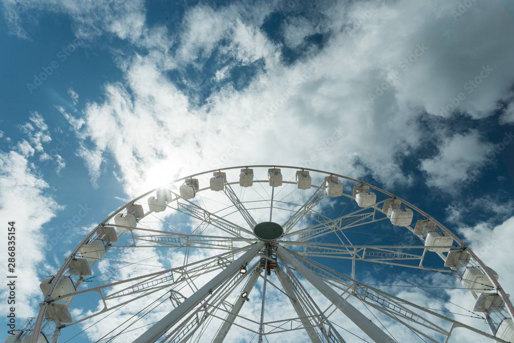 Ferris wheel on the blue cloudy sky. Background concept of happy holidays time. Ferris wheel on the blue cloudy sky. Background concept of happy holidays time.