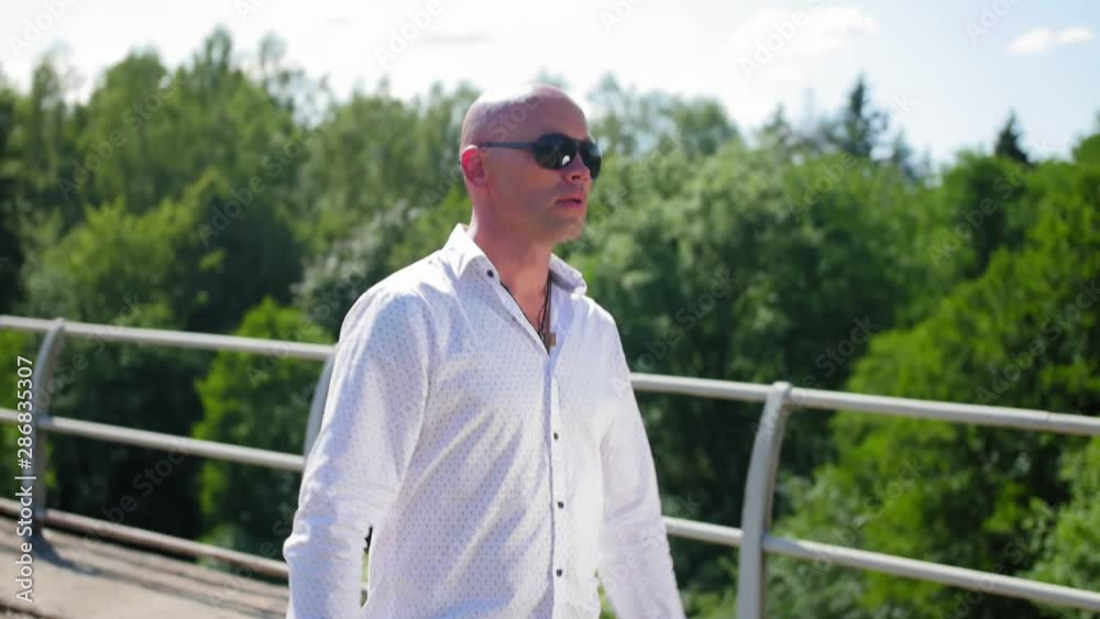 A bald man going along on an abandoned railway bridge and sings. Medium shot. A bald man going along on an abandoned railway bridge and sings. Medium shot.