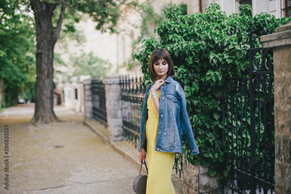 Beautiful woman in yellow jumpsuit posing on city streets. Beautiful woman in yellow jumpsuit posing on city streets.