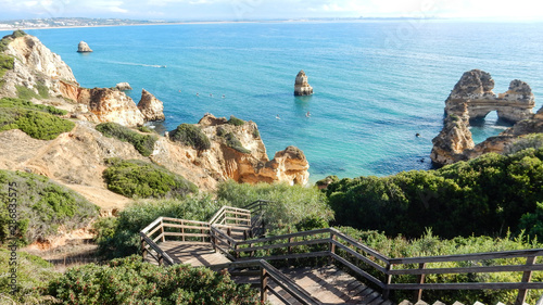 Panoramic view of the ocean cliffs of the Algarve, Portugal, with orange rocks on the blue sea