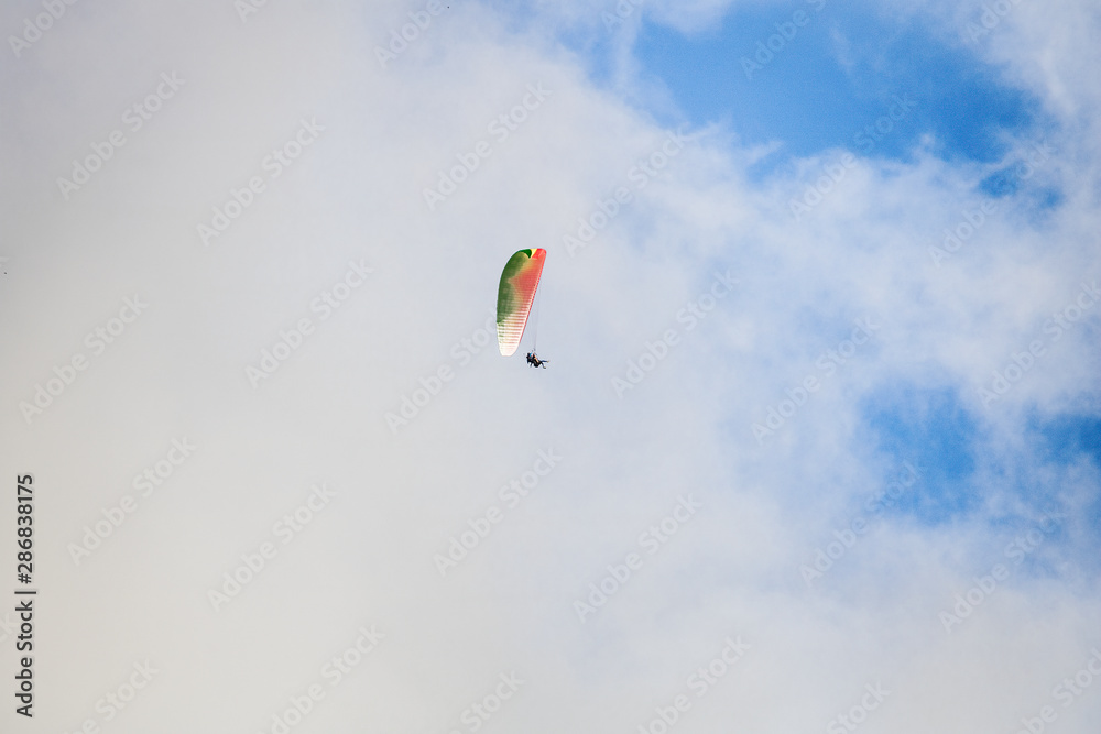Paraglider floating through clouds and blue sky over Camps Bay, Cape Town. Paraglider floating through clouds and blue sky over Camps Bay, Cape Town.